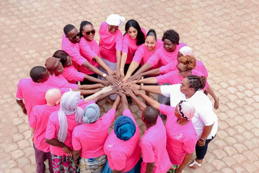 Membres et bénévoles d’OFIDEF en t-shirts roses, mains réunies en signe de solidarité